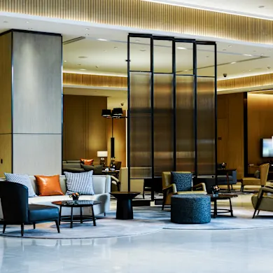Espace lounge d'un bureau flexible à Bruxelles : fauteuils design, canapés et verrière en verre cannelé